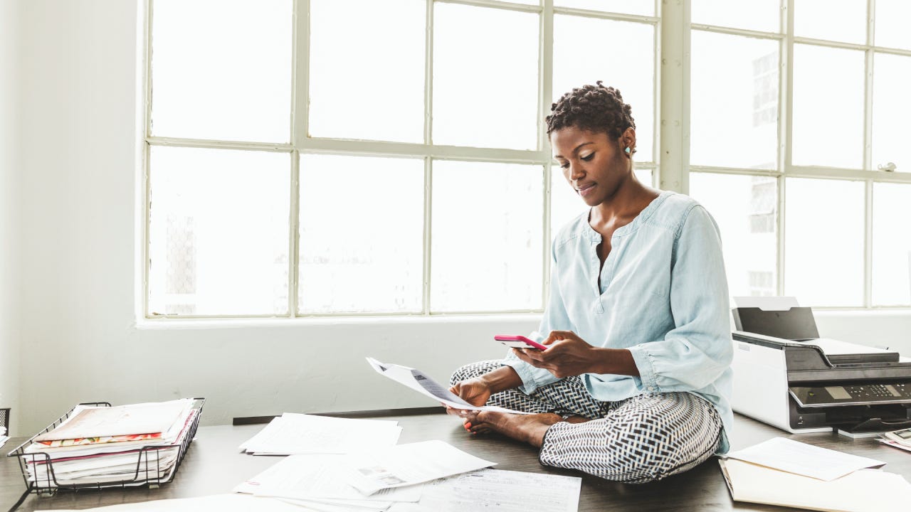 Female entrepreneur using smart phone while sitting on desk in office