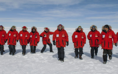 A row of people in red cold weather clothing in an icy landscape