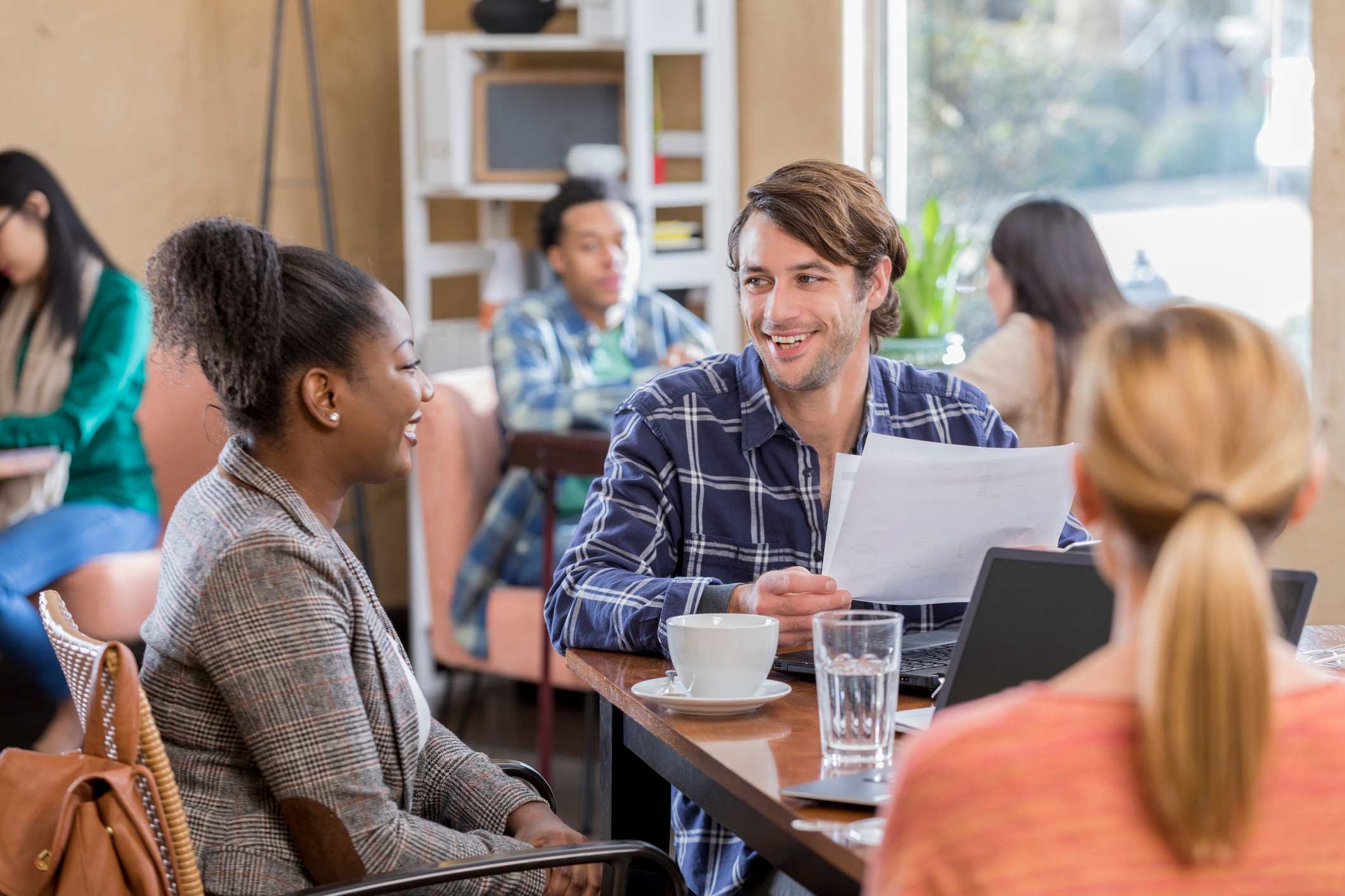 Two-coworkers-smiling-while-interviewing-a-woman-on-a-cafe-internal-interview-questions