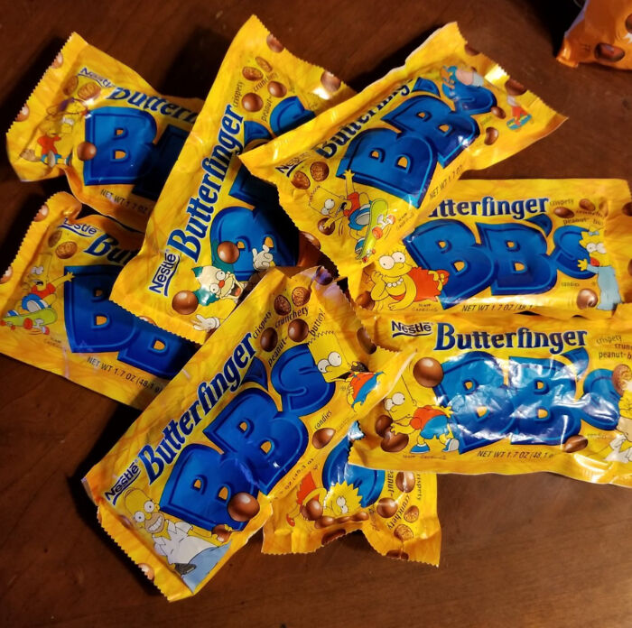 Butterfinger BB's on a table, illustrated yellow packaging featuring retro 90s designs, evoking nostalgic 90s foods.