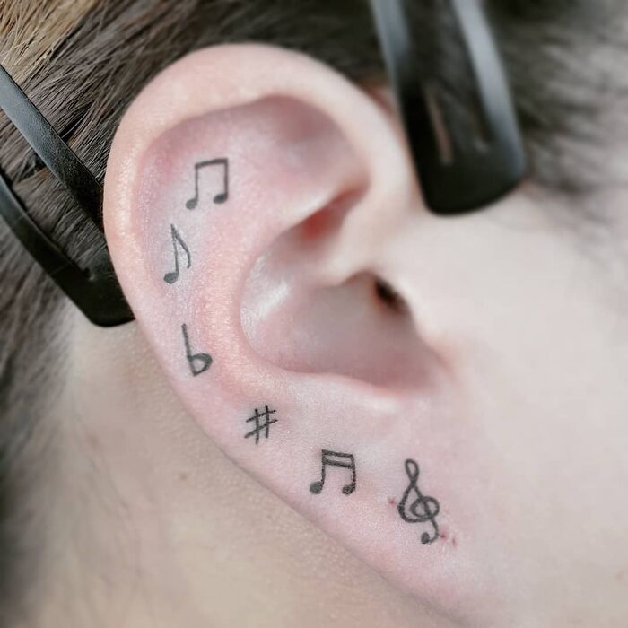 Music tattoos of notes and symbols inked on an ear.