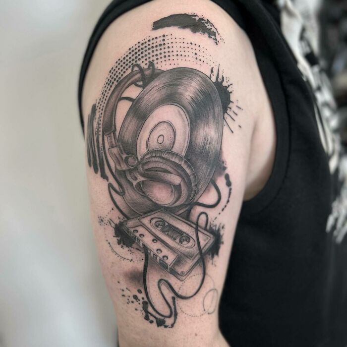 Arm tattoo of a vinyl record, headphones, and cassette; a creative example of music tattoos.