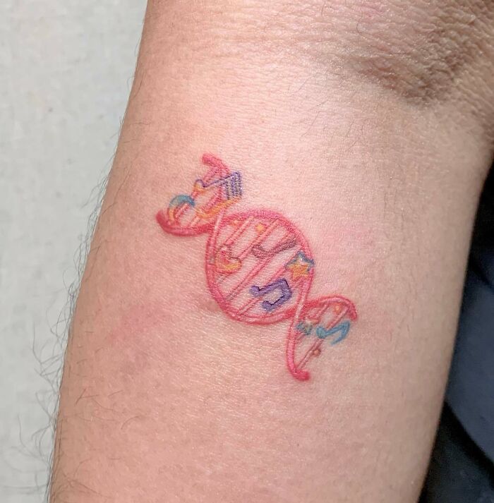 Colorful candy-shaped music tattoo featuring musical notes on forearm.