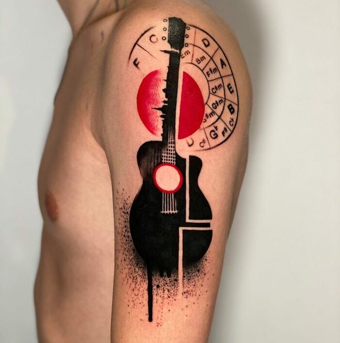 Abstract guitar music tattoo with red accents and chord chart on arm.