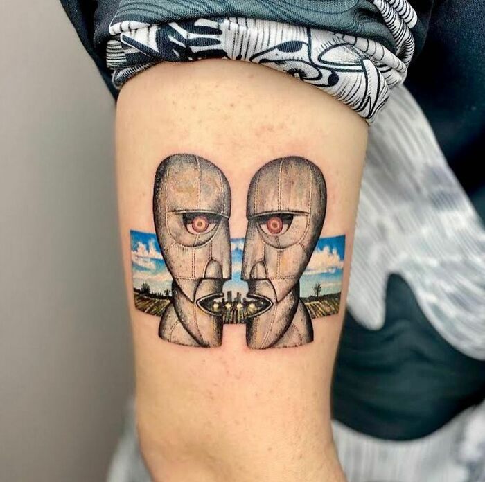 Tattoo of two faces with a surreal landscape design, symbolizing music inspiration.