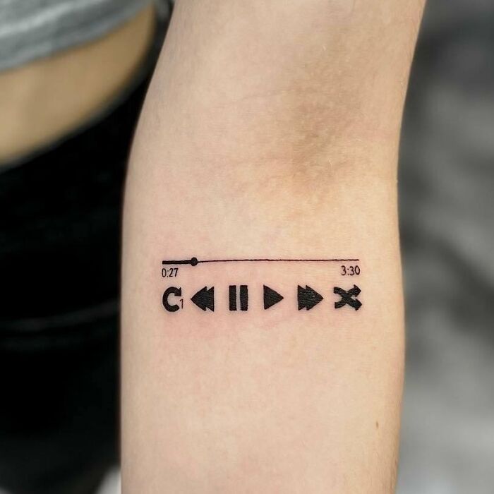 Music tattoo with play buttons on an arm, symbolizing love for music.