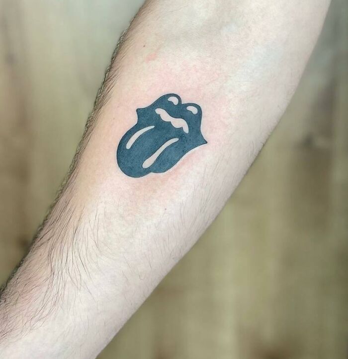 Music tattoo of a tongue and lips design on a person's forearm.