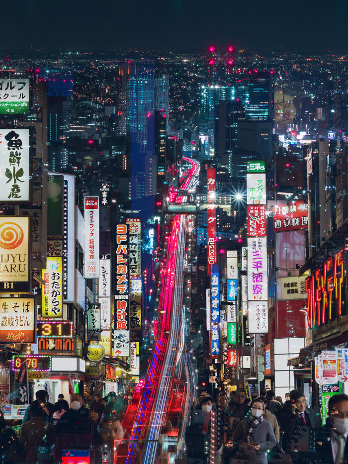 Neon-lit street in Tokyo at night bustling with people, showcasing incredible world photos' vibrant city life.