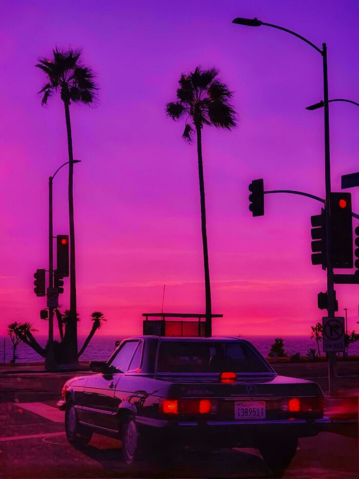 Classic car at sunset with palm trees, vibrant purple sky, highlighting incredible world photos aesthetic.