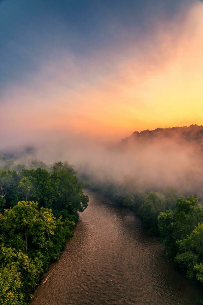 Sunrise over a serene river and forest, creating an ethereal atmosphere, showcasing incredible world photography.