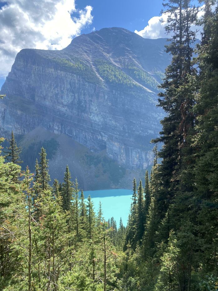 Turquoise lake surrounded by pine trees and majestic mountain, showcasing incredible world photos.