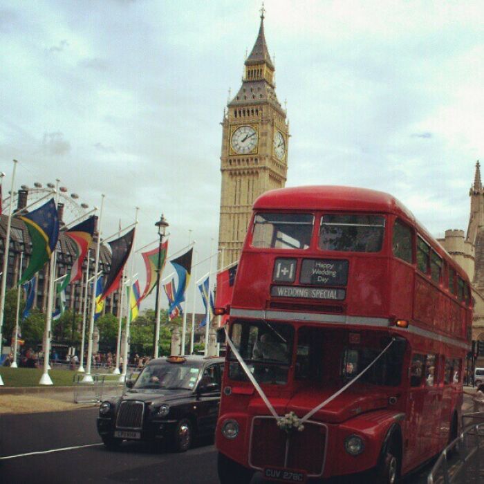 Red double-decker bus in front of Big Ben with flags, capturing incredible world moments.