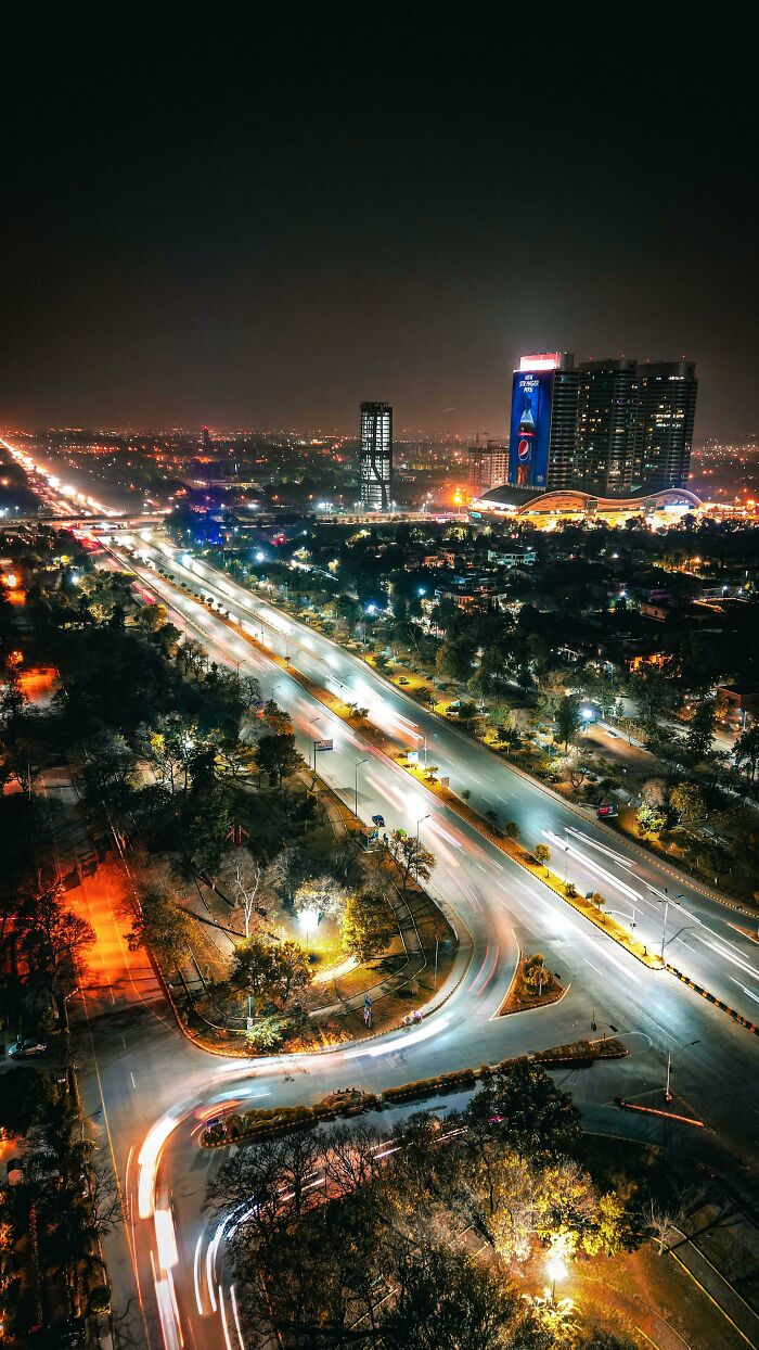 Aerial view of a vibrant city at night with illuminated roads and buildings, showcasing incredible world photos.