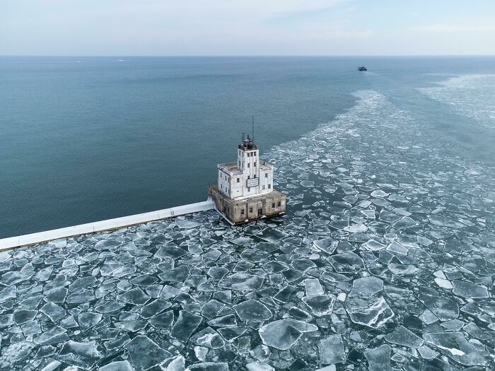 Lighthouse surrounded by icy water, showcasing an incredible world photo.