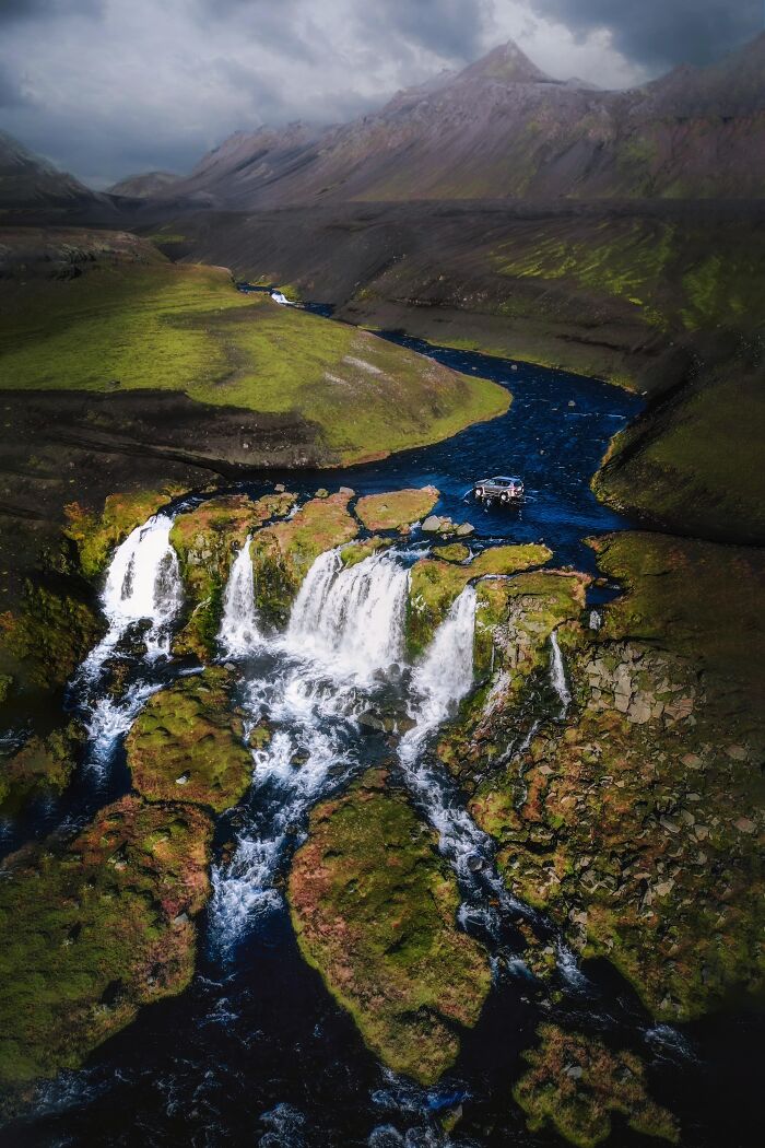 Aerial view of a stunning waterfall and river in a mountainous landscape, showcasing incredible world photos.