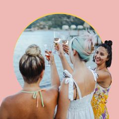 women on a bachelorette party toasting wine glasses by a lake