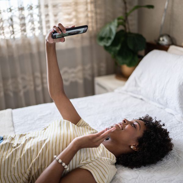 Woman Lying on Bed While FaceTiming Her Partner