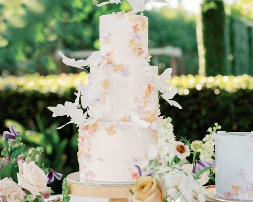 three-tier wedding cake decorated with flowers and butterfly motifs