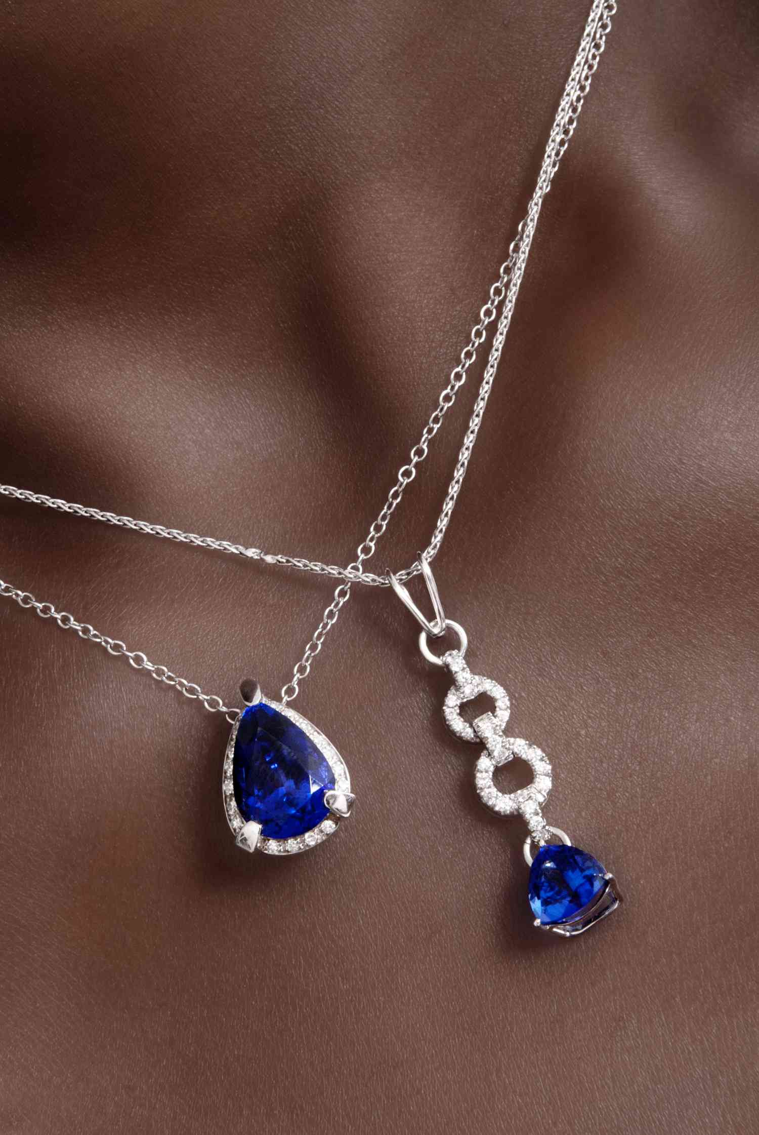 A close-up shot of two necklaces with diamond and sapphire gemstones on silver chains