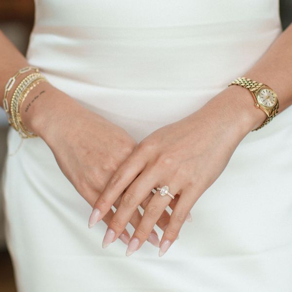 Closeup of Hands With French Manicure, Oval-Shaped Diamond Ring, Gold Watch, and Gold Bracelets