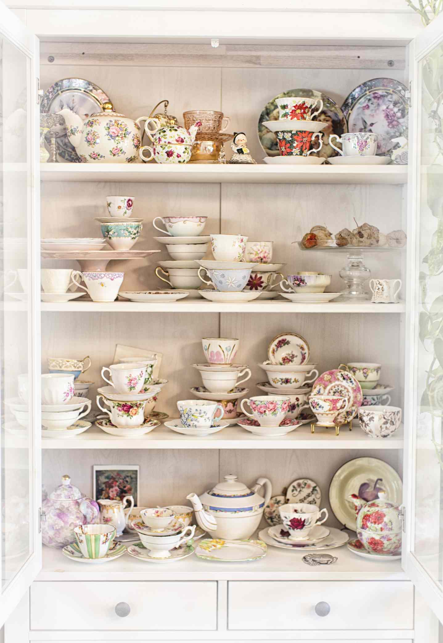 China cabinet with antique tea cups and plates in colorful patterns