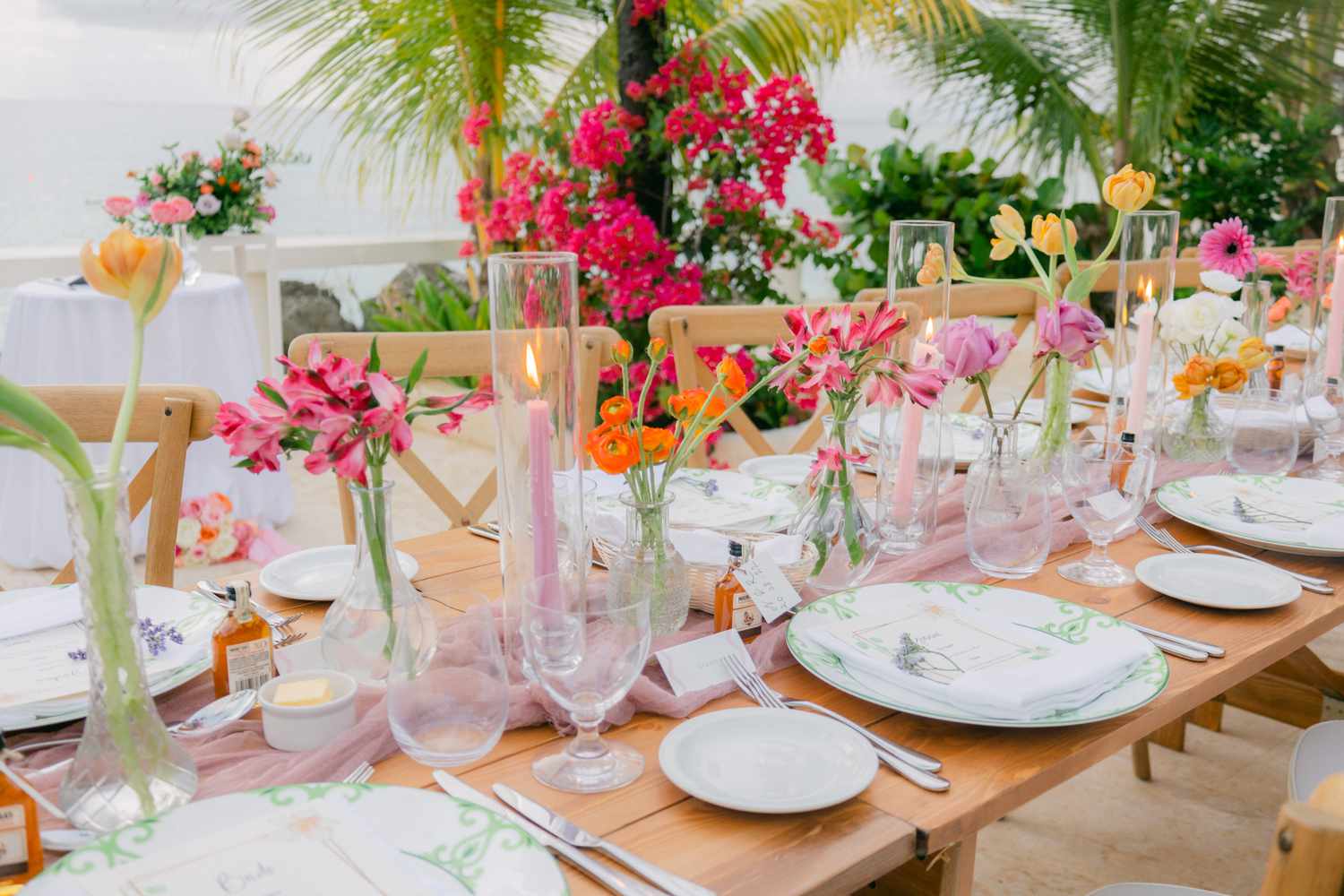 Reception tables lined with colorful flowers and pink taper candles