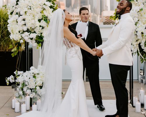 bride and groom holding hands during wedding ceremony on rooftop