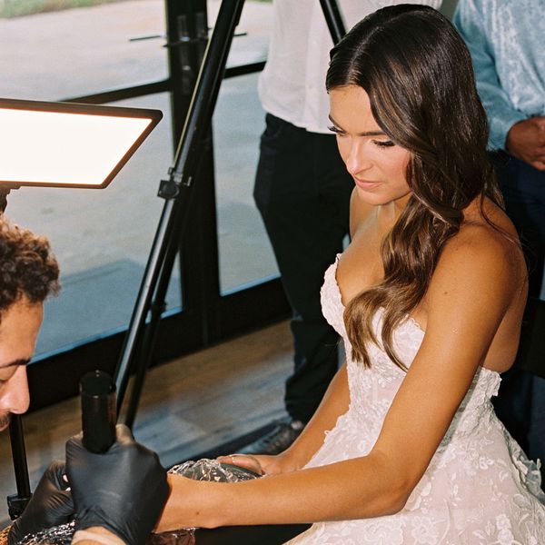 bride getting a wedding ring tattooed during her reception