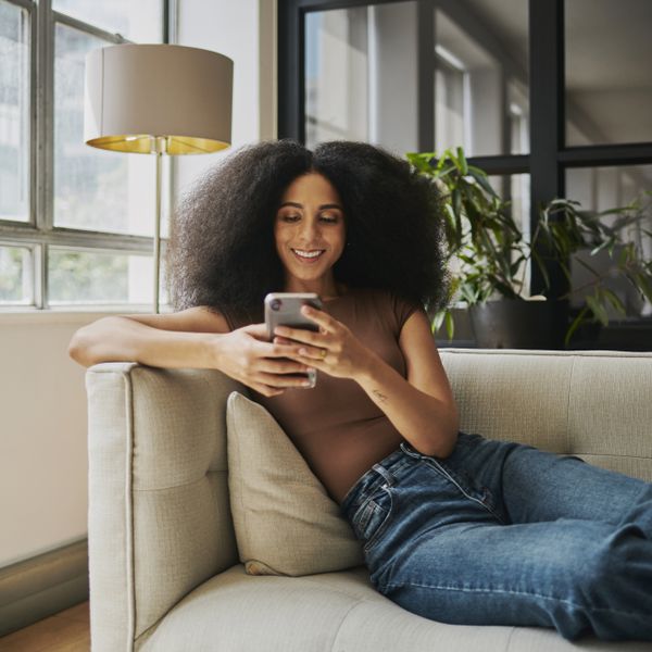 A woman sitting on the couch while texting on her cell phone