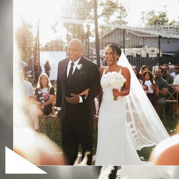 Bride in White Wedding Dress And Long Veil Holding Bouquet Walking Down Aisle With Father in Black Tuxedo 