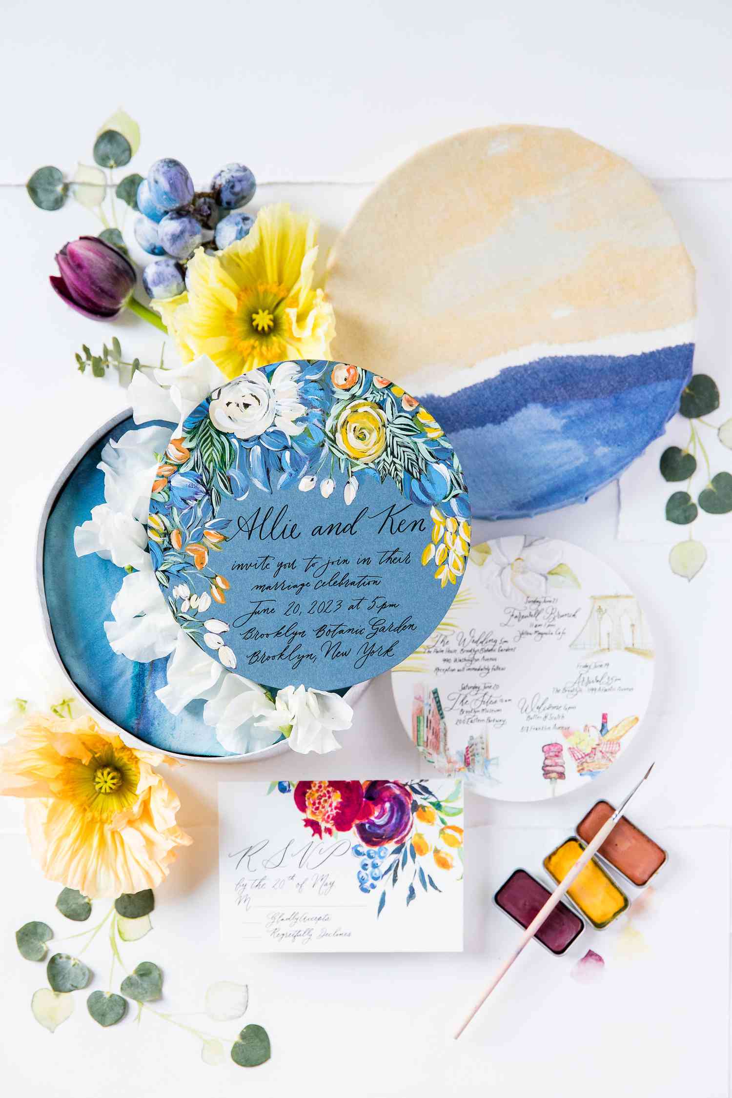 A circular boxed wedding invitation with hand-painted details.