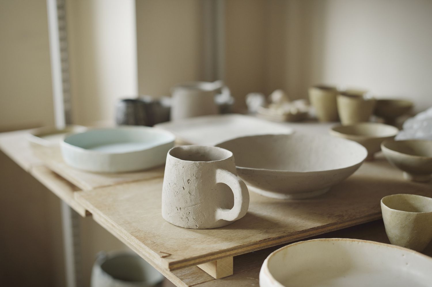 Pottery cups and plates on a wooden board in a studio 