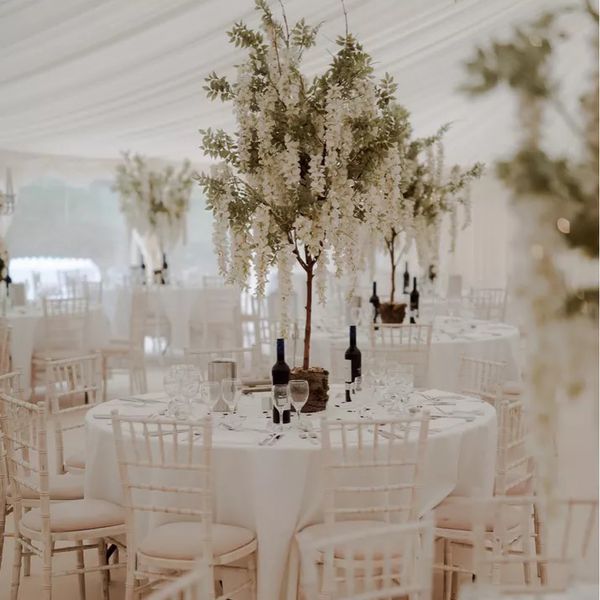 All white wedding decor including white tables, white chairs, and white hanging flowers