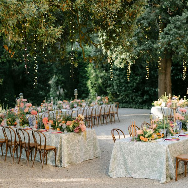 Twinkle Lights Hang From Trees Above Tables Set for an Outdoor Dinner Reception