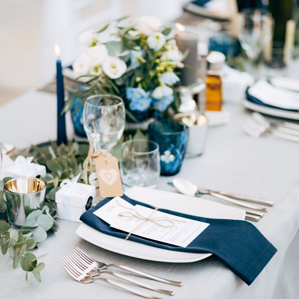 A wedding reception table design with floral arrangements, place settings, and glassware.