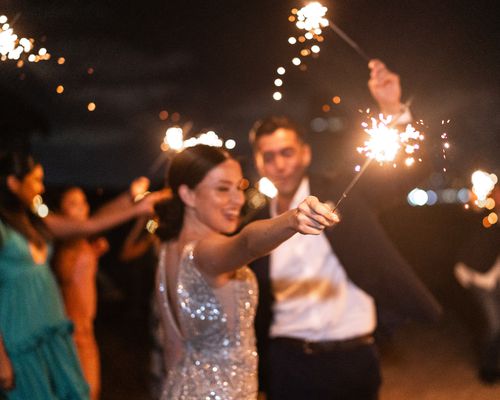 bride and groom waving sparklers while exiting their wedding