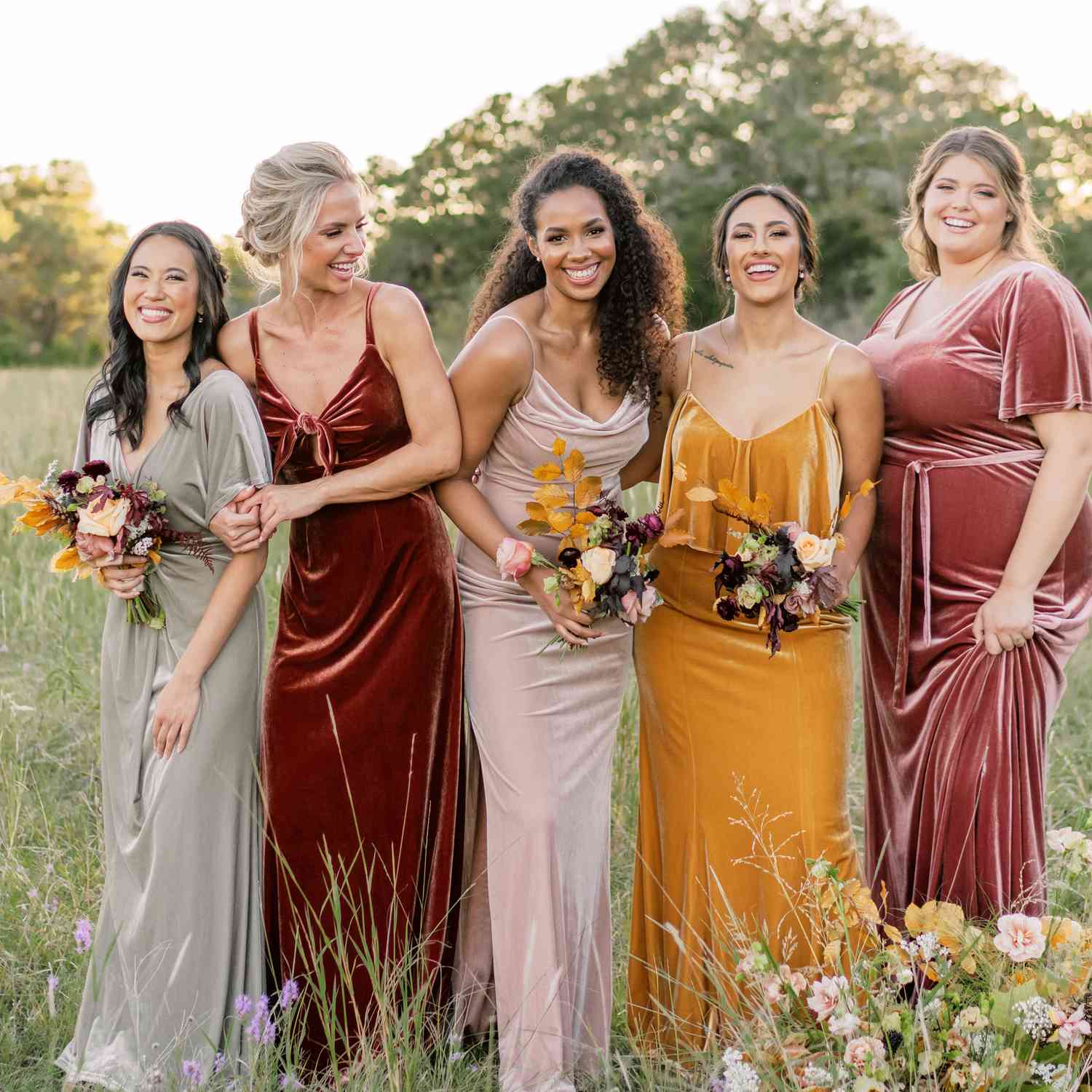 Group of bridesmaids wearing Revelry velvet dresses standing in a field