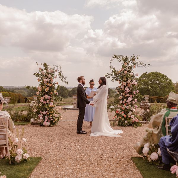 Bride and Groom Holding Hands During Outdoor Wedding Ceremony Marked by Fresh Flowers