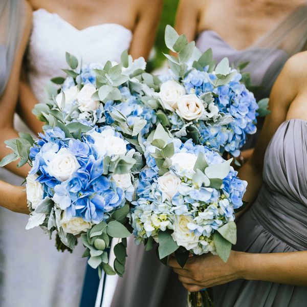 High angle view of bride and bridesmaids holding blue and white flower bouquets.