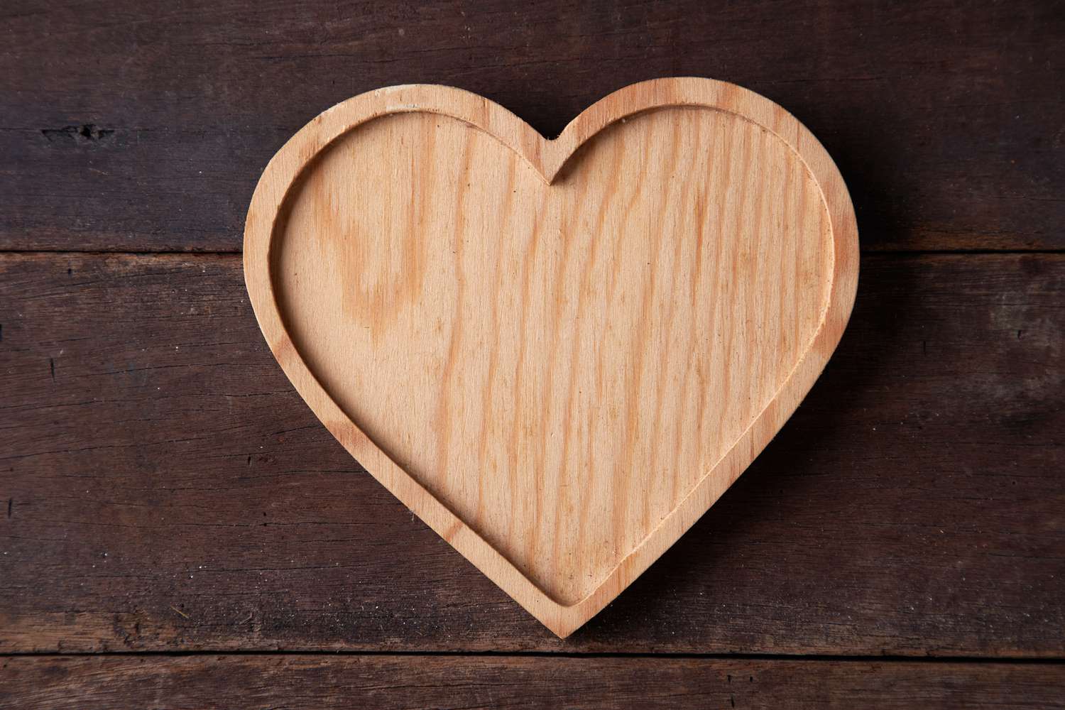 Wooden heart-shaped tray on top of wooden plank representing the fifth marriage anniversary