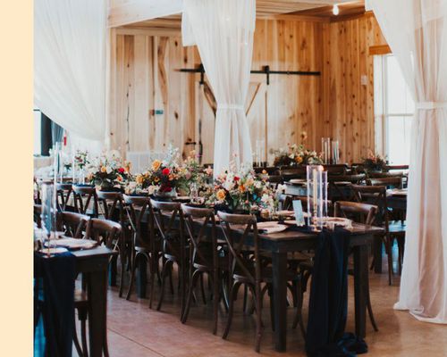 Dark Wood Wedding Reception Table With Black Runner, Red and Yellow Centerpieces, and Draping