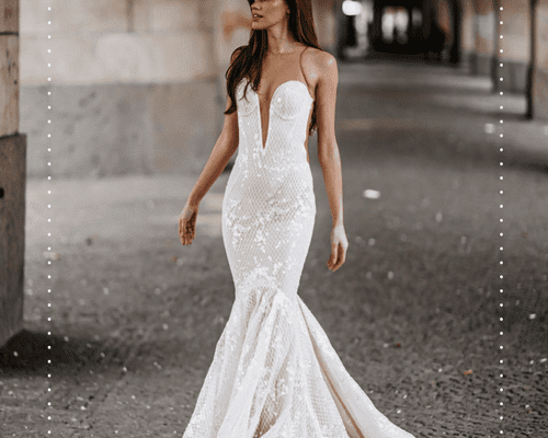 Bride wearing a white sparkly wedding dress while standing near stone outdoor arcade arches