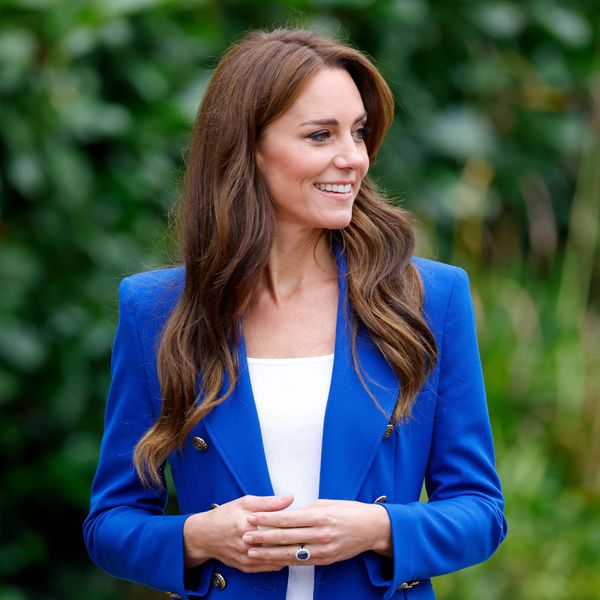 Kate Middleton standing outside with hands clasped and showing her diamond and sapphire engagement ring