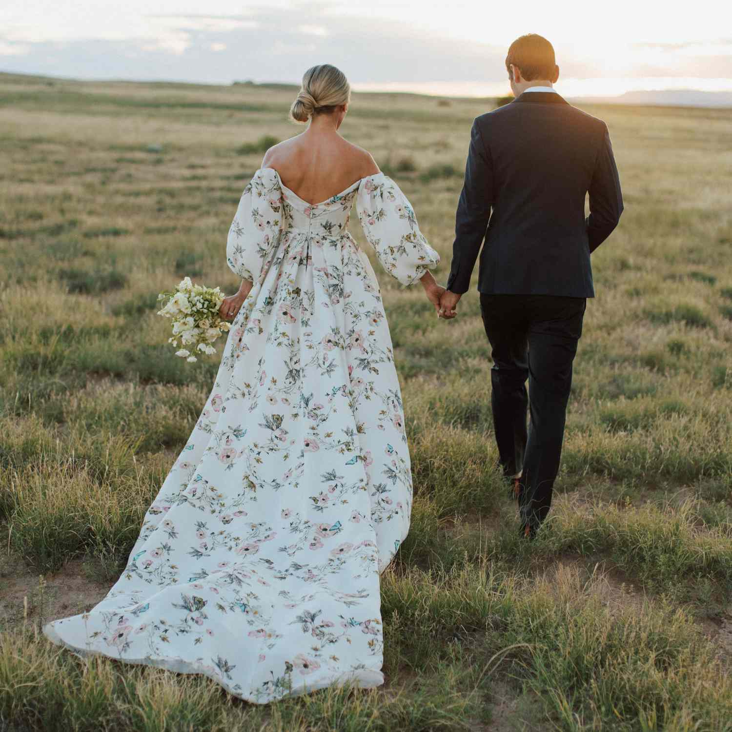 bride and groom holding hands walking towards the sunset