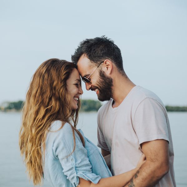 Man and Woman Touching Foreheads in Front of Body of Water