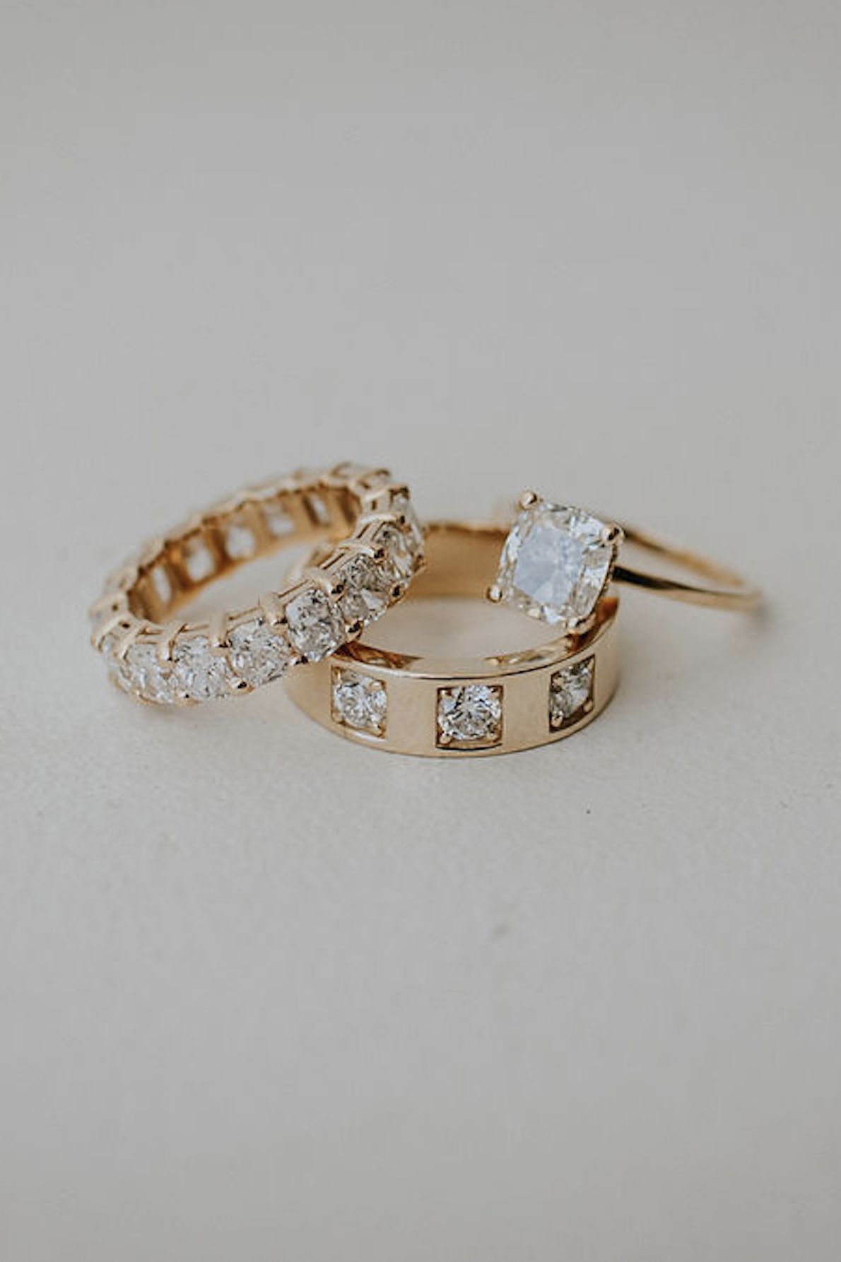 two gold and diamond wedding bands with a cushion-cut diamond engagement ring sitting on top