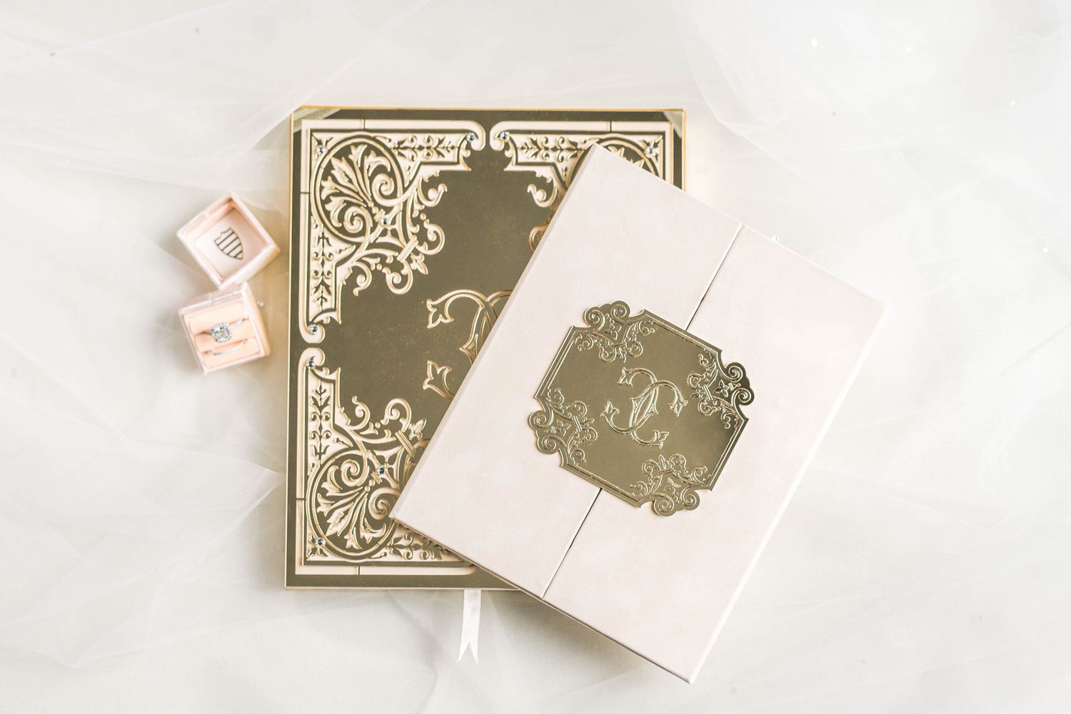 A gold boxed wedding invitation featuring a custom crest.