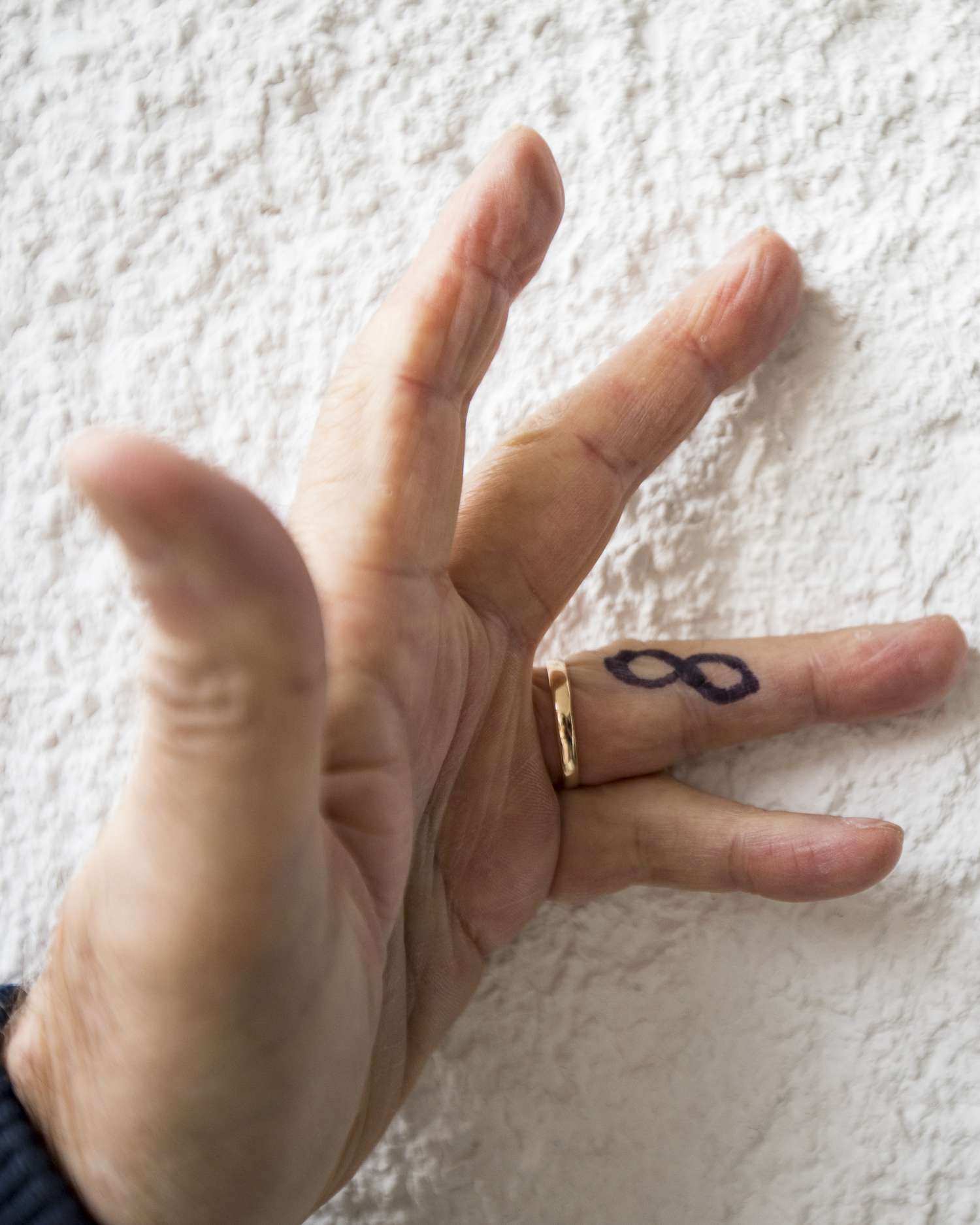 Man's Hand With Infinity Symbol Tattoo on Finger