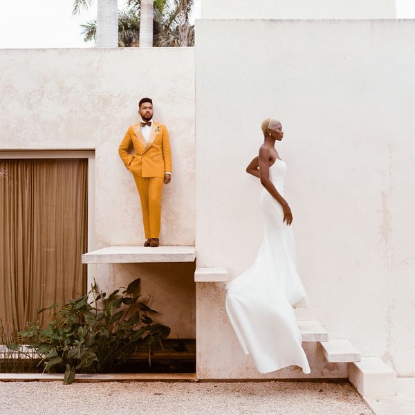 Bride in Strapless Wedding Dress and to Groom in Mustard Yellow Tuxedo Posing on Stairs