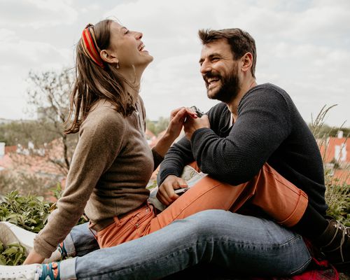 happy couple sitting outdoors on a beautiful day flirting on the fence